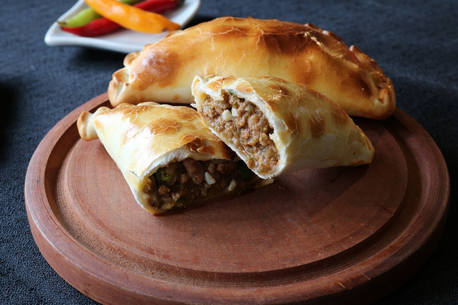 Empanadas de carne de Fugacheta cortadas al medio, mostrando el relleno jugoso, servidas con ají