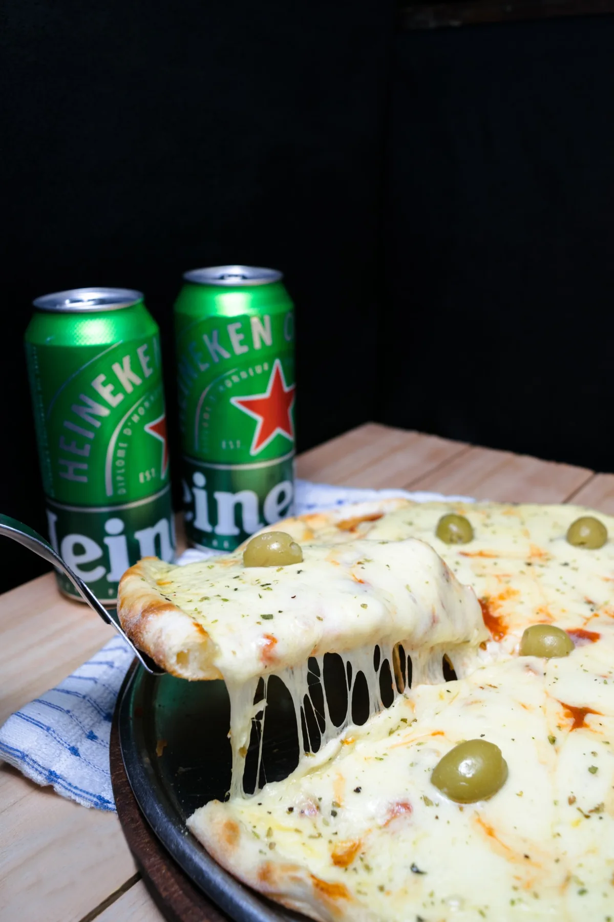 Porción de pizza a la piedra de muzzarella con aceitunas, tirando hilos de queso